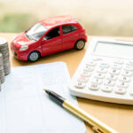 A toy car next to money and a calculator.